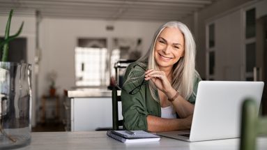 successful older woman laughing and smiling while working at home