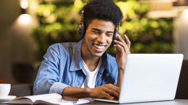 young black guy with headset looking at laptop